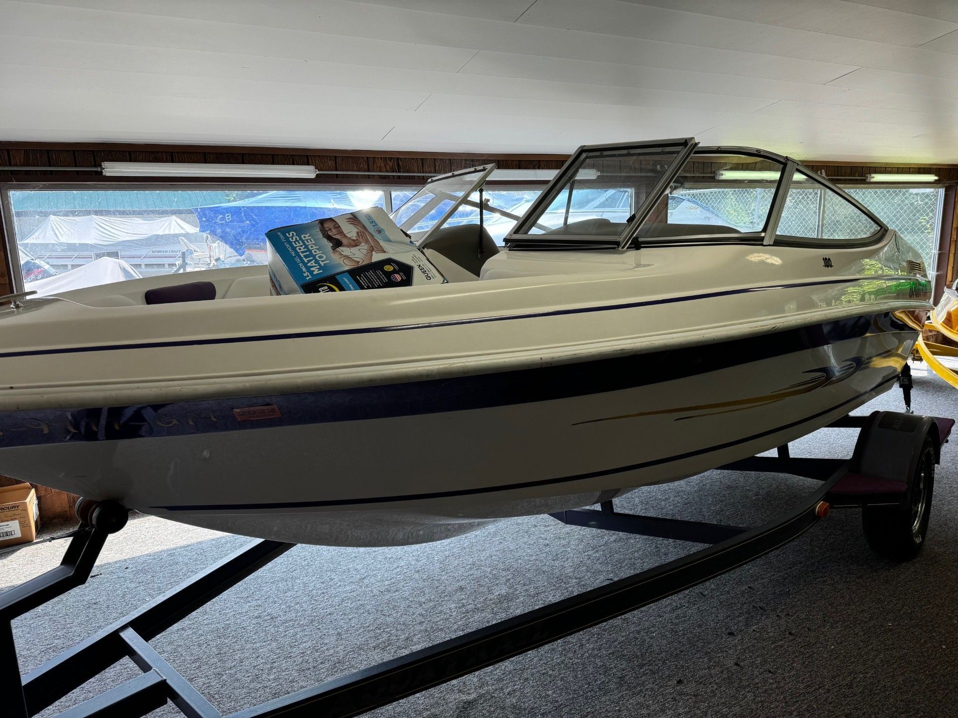 A white boat is sitting on a trailer in a garage