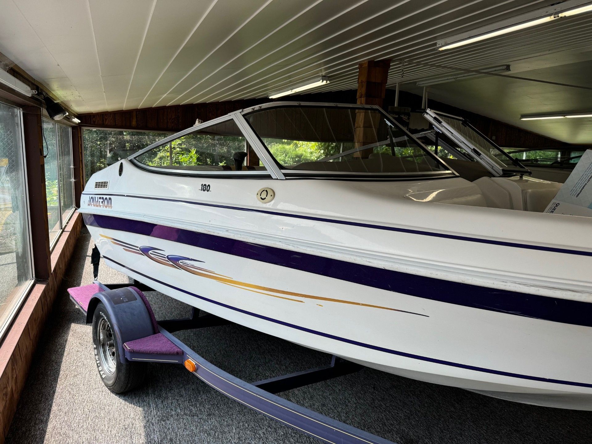 A white and purple boat is sitting on a trailer