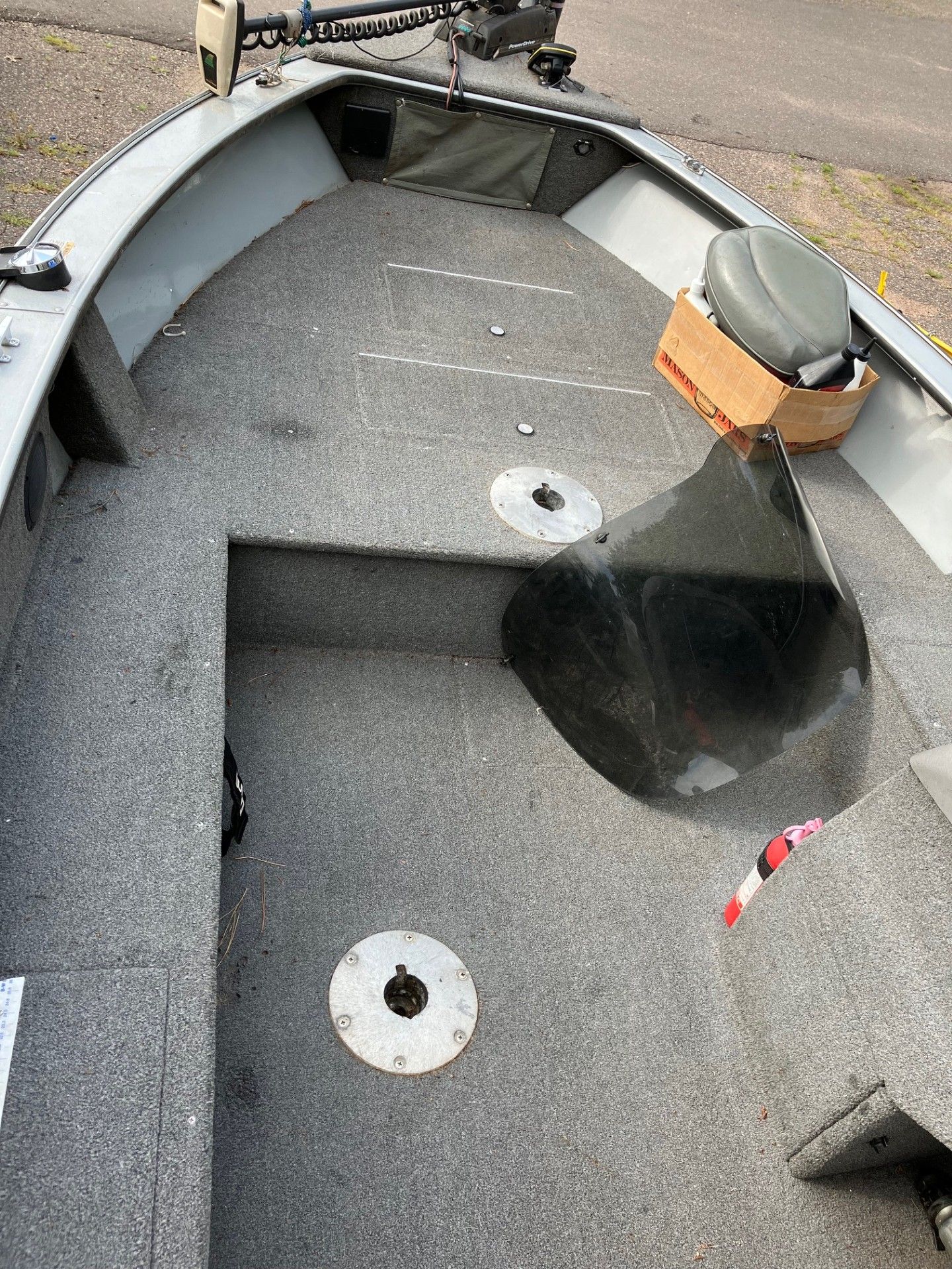 Inside view of a gray fishing boat with carpet flooring and a motor attached.
