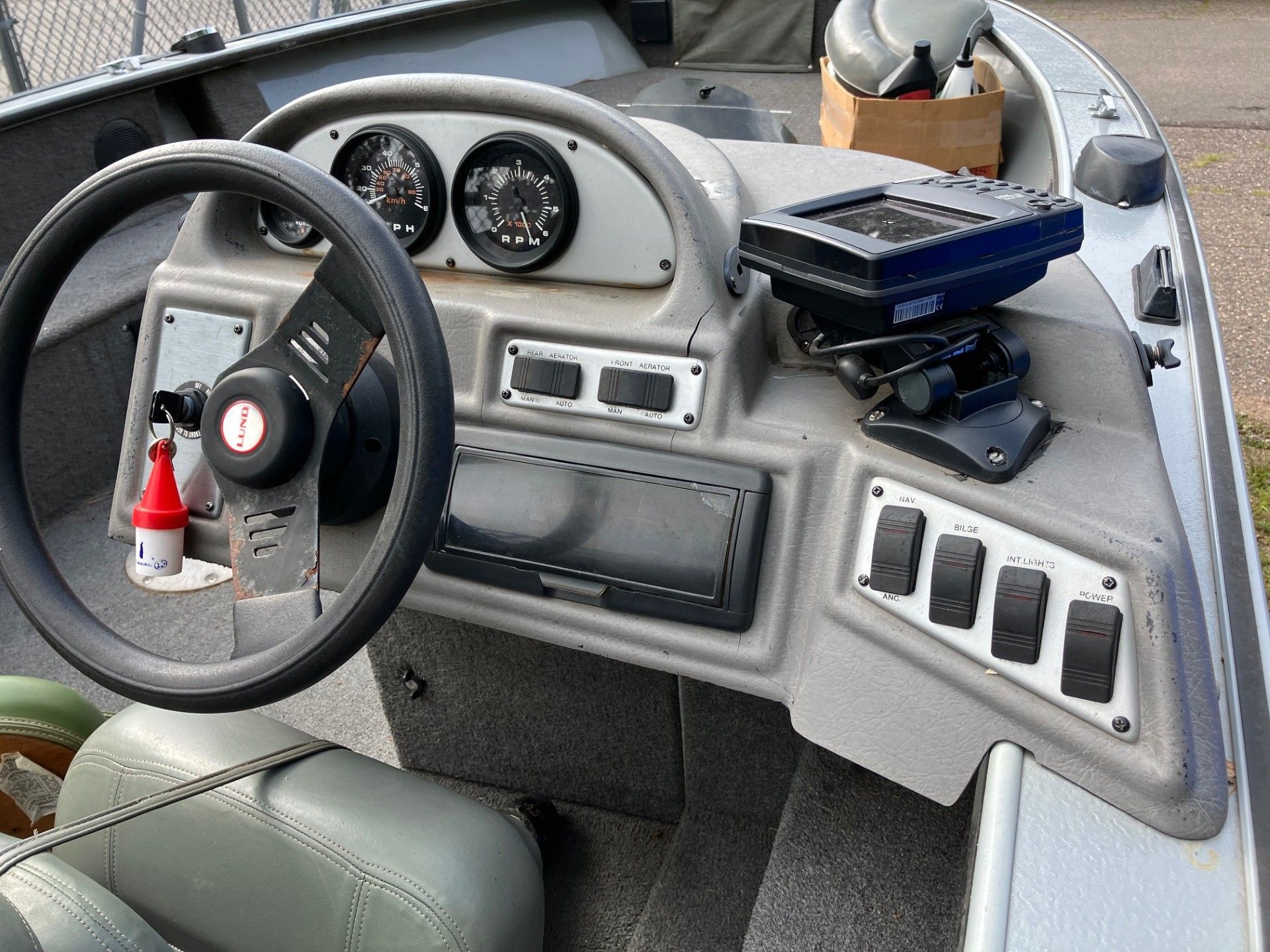 Boat dashboard with steering wheel, gauges, and electronics.
