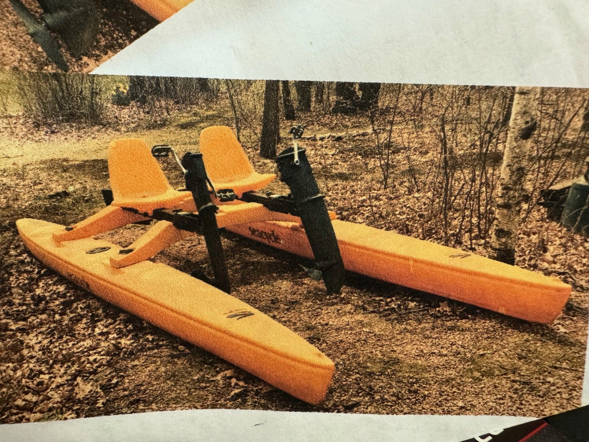 A yellow sea cycle water bike is sitting on the ground in the woods