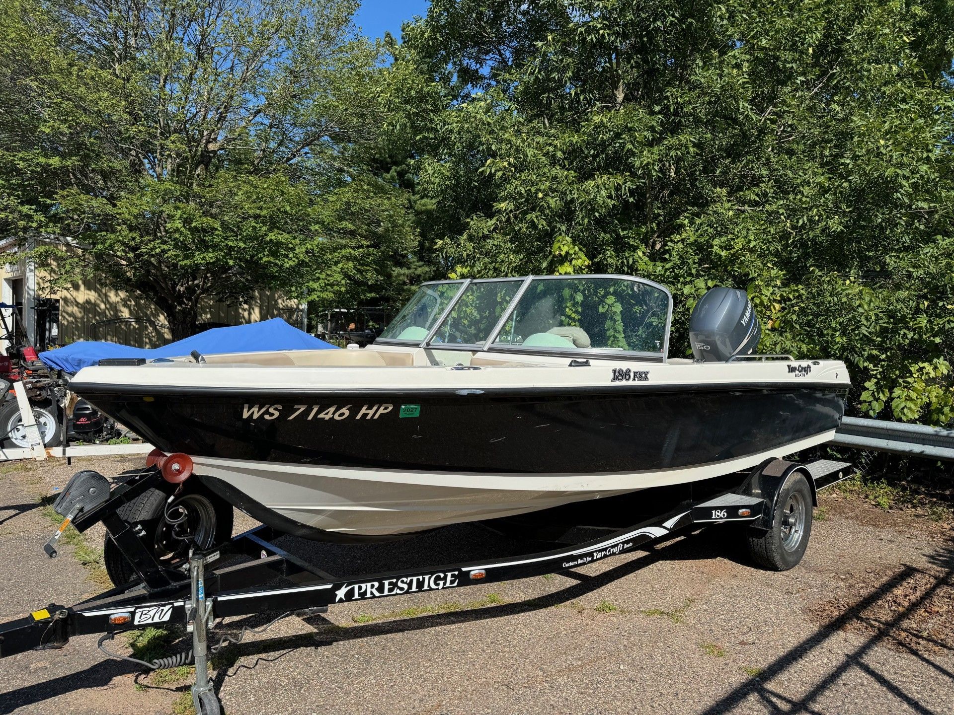 A small boat is parked on a trailer in a parking lot.