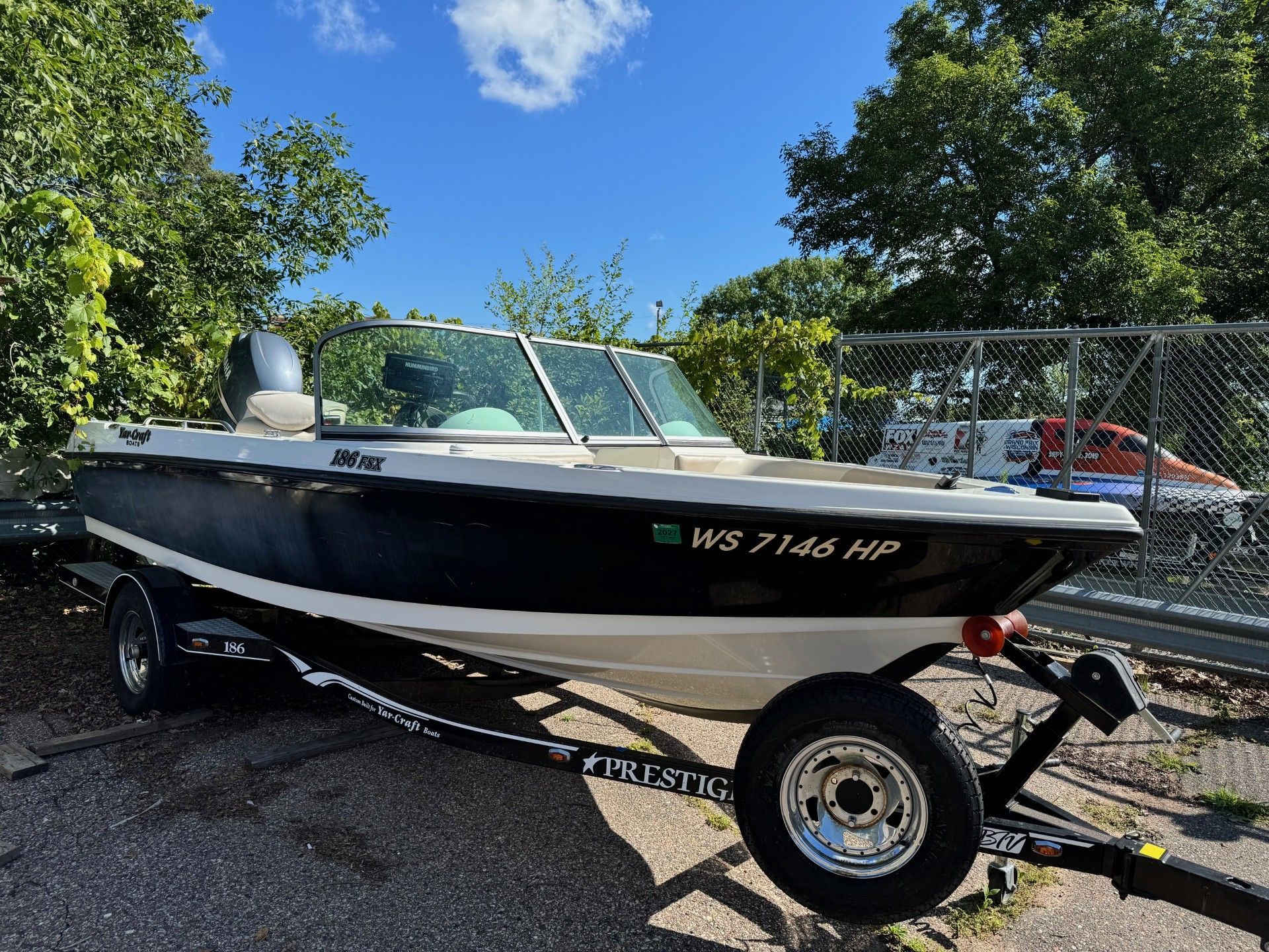 A small boat is parked on the side of the road on a trailer.