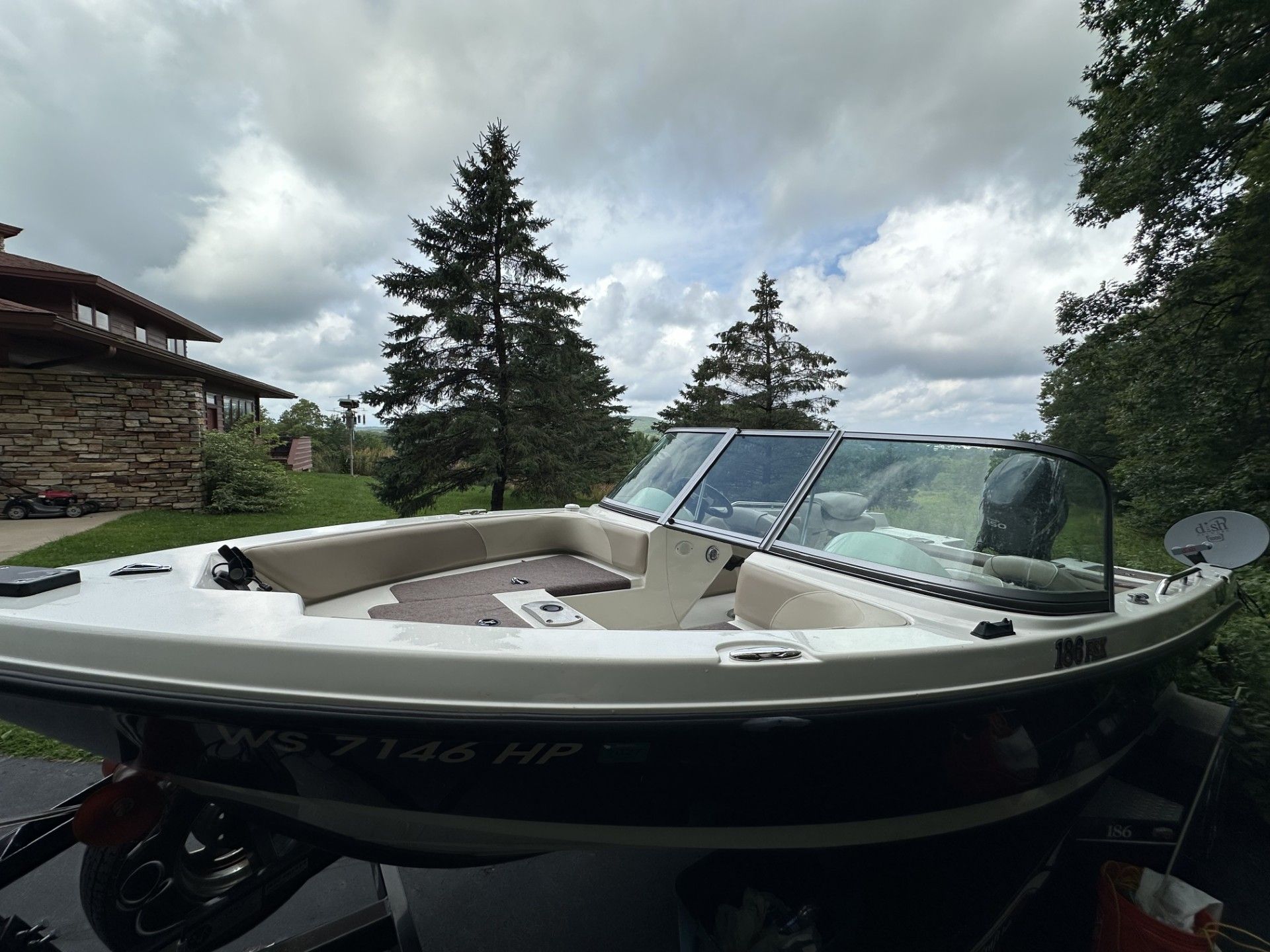 A boat is parked in front of a house with trees in the background.