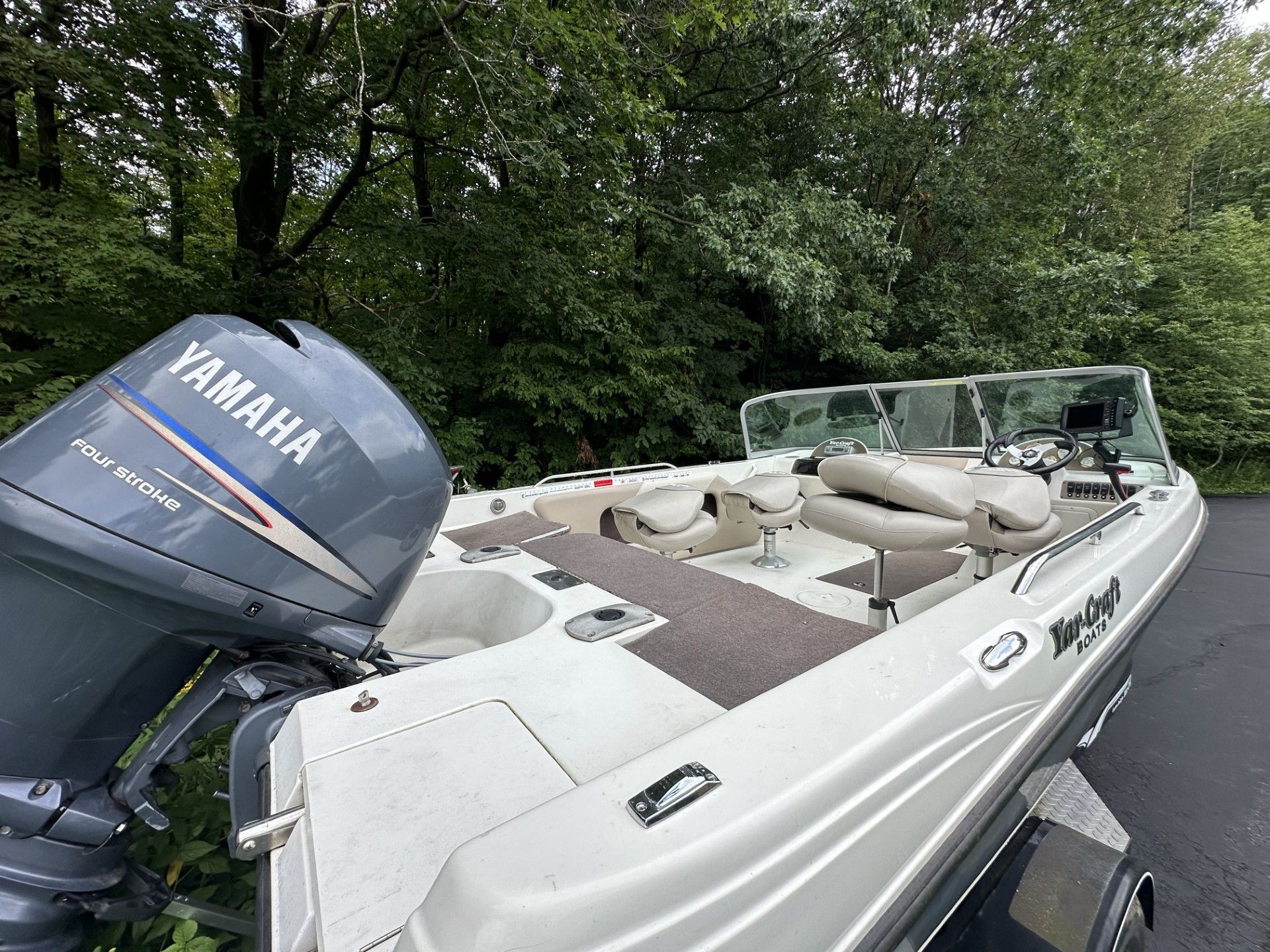 A white boat with a yamaha engine is parked in a parking lot.