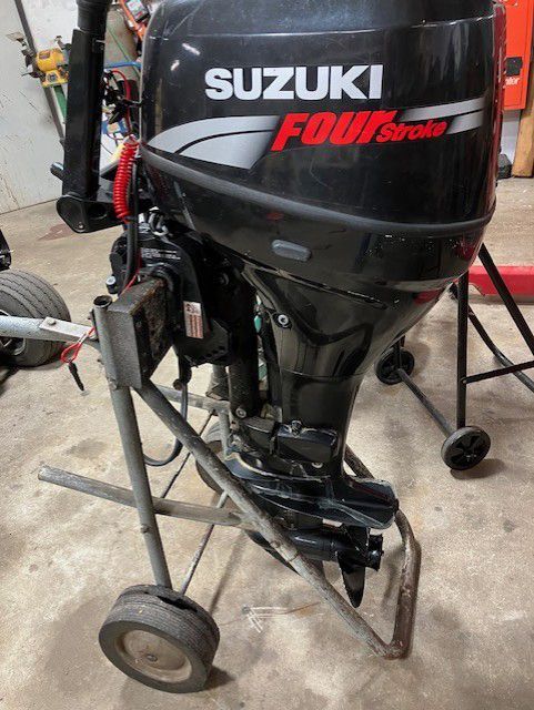 A suzuki outboard motor is sitting on a cart