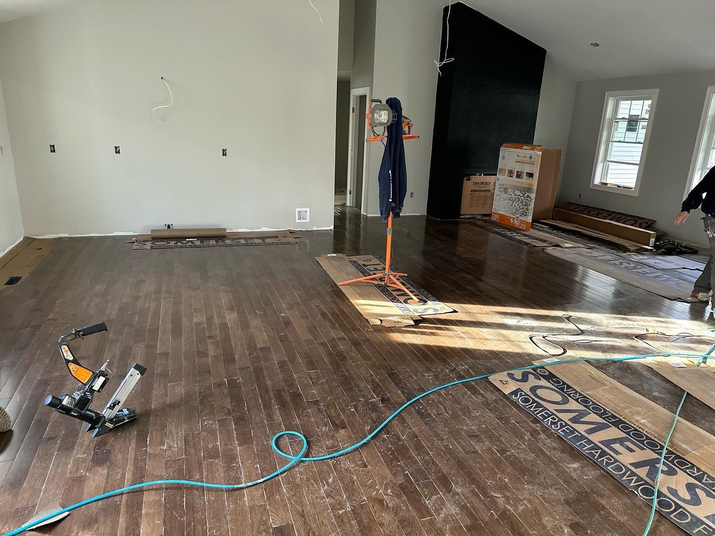 Partially renovated room with tools, exposed floorboards, and a TV mounted on the wall