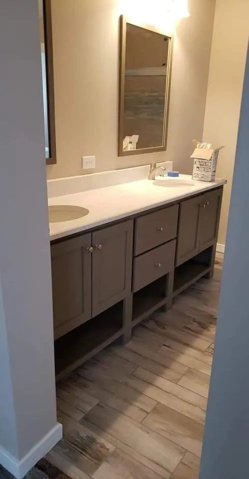 Bathroom vanity with dark cabinets, white countertop, sink, and mirror against beige walls