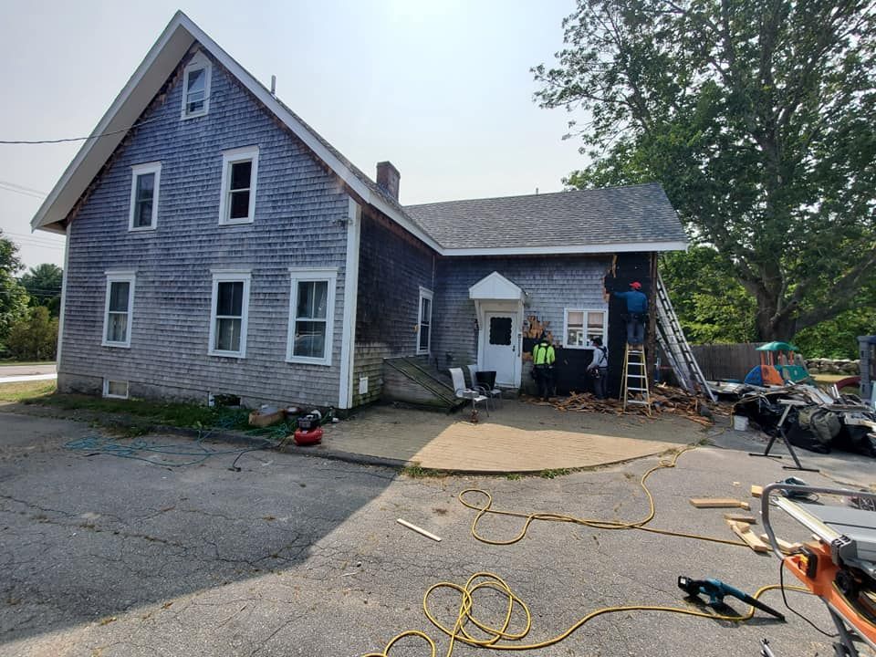 Blue house under exterior repair with ladders, tools, and construction materials in the driveway