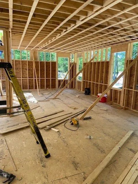 Partially framed house interior with exposed ceiling joists, tools, and lumber on the floor