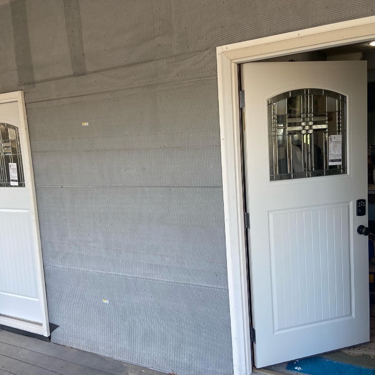 Open white door with window panes in a gray screened porch area.