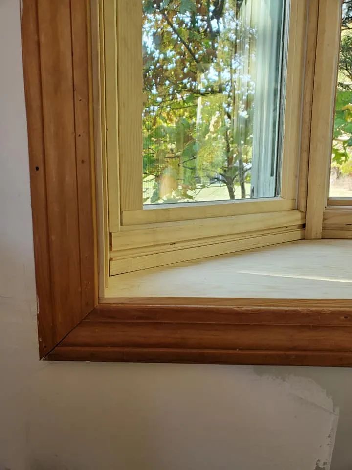 Wooden window frame with white trim overlooking trees outside