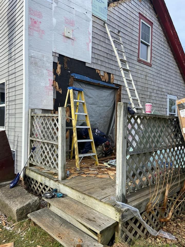 Partially demolished house entry with ladder, tarp, and wooden steps behind a lattice fence