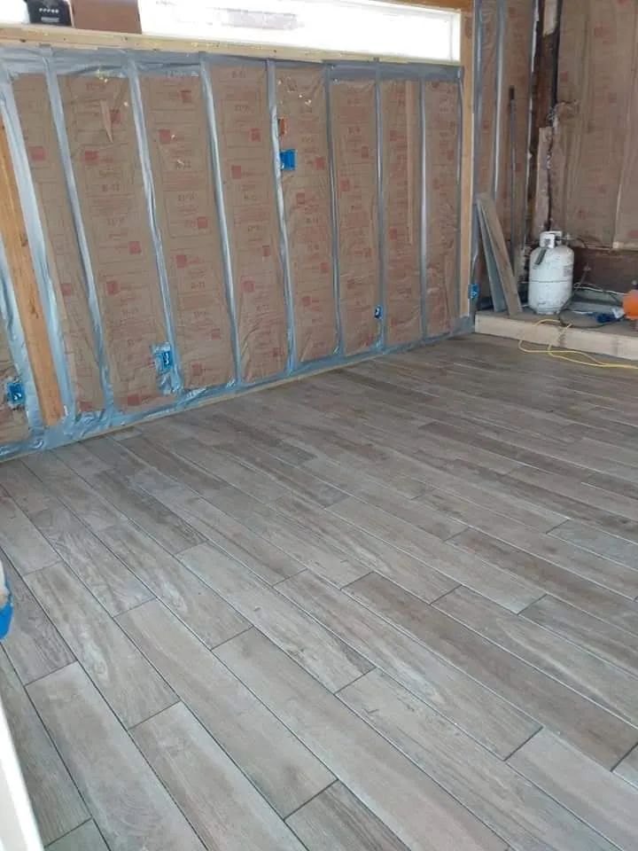 Unfinished room with exposed wall insulation, wood floor, and a white propane tank in the corner