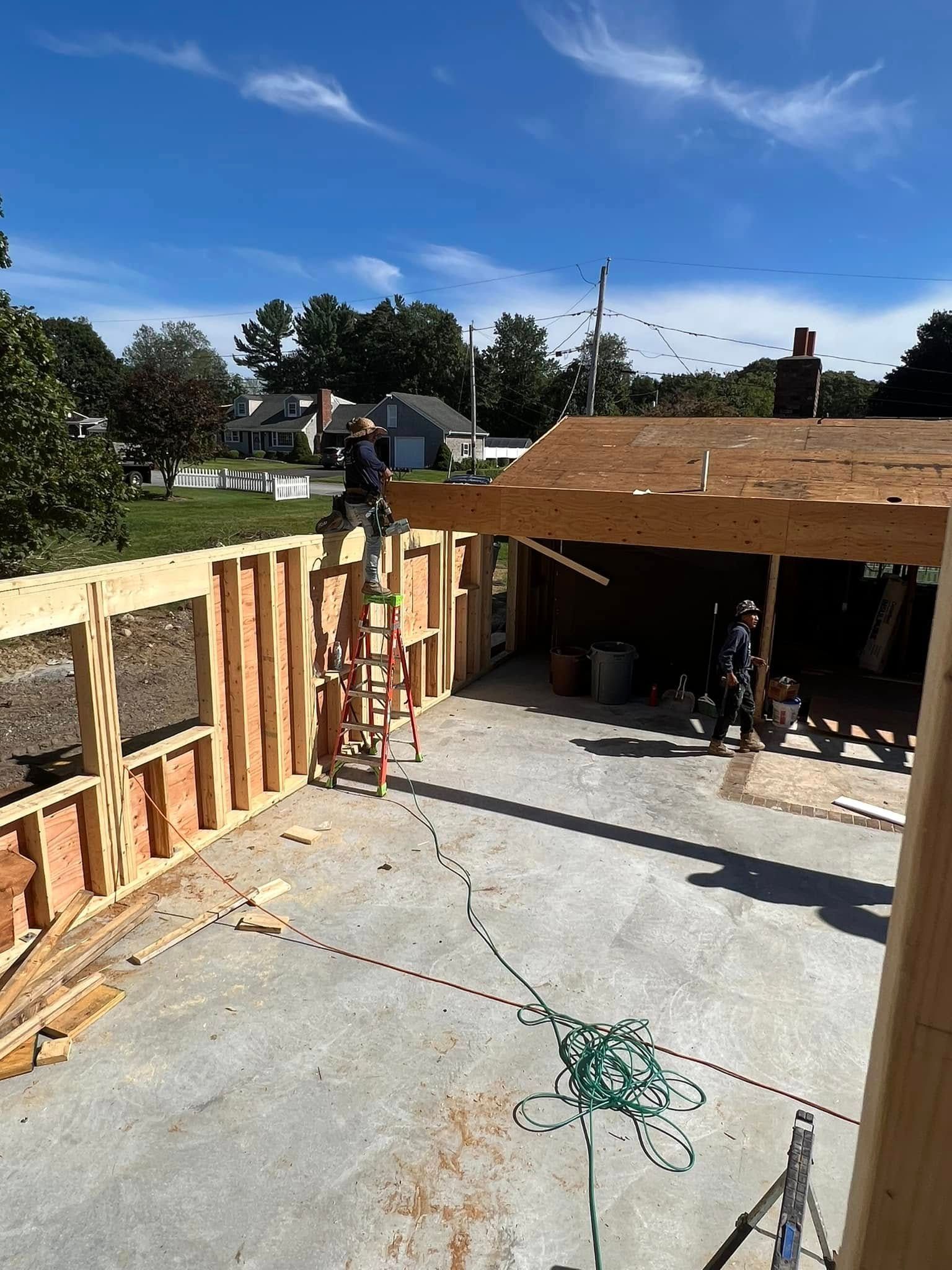 Construction site with wooden framing and concrete slab under a bright blue sky.