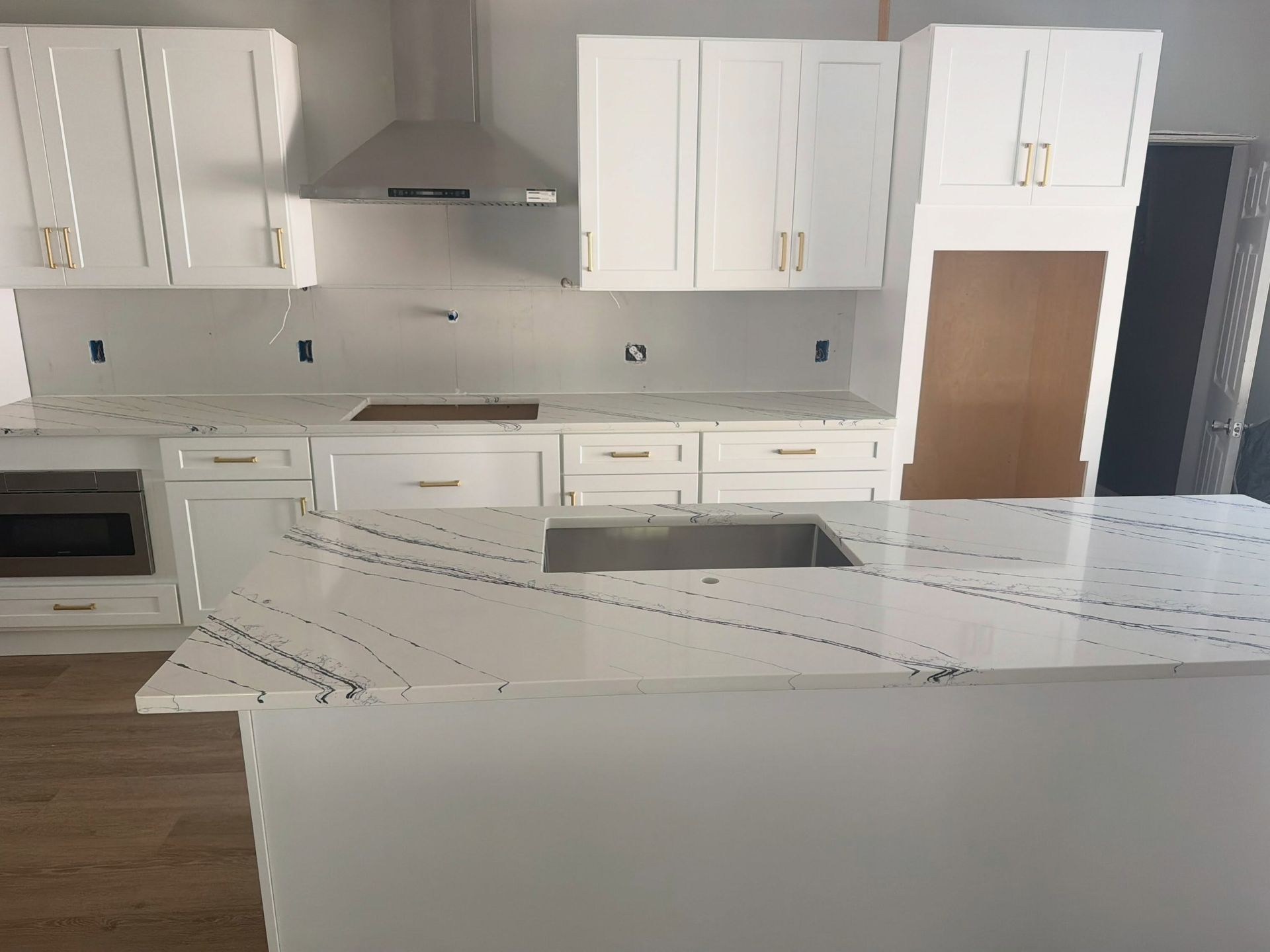 Bright modern white kitchen with island, stainless range hood, and wood floors