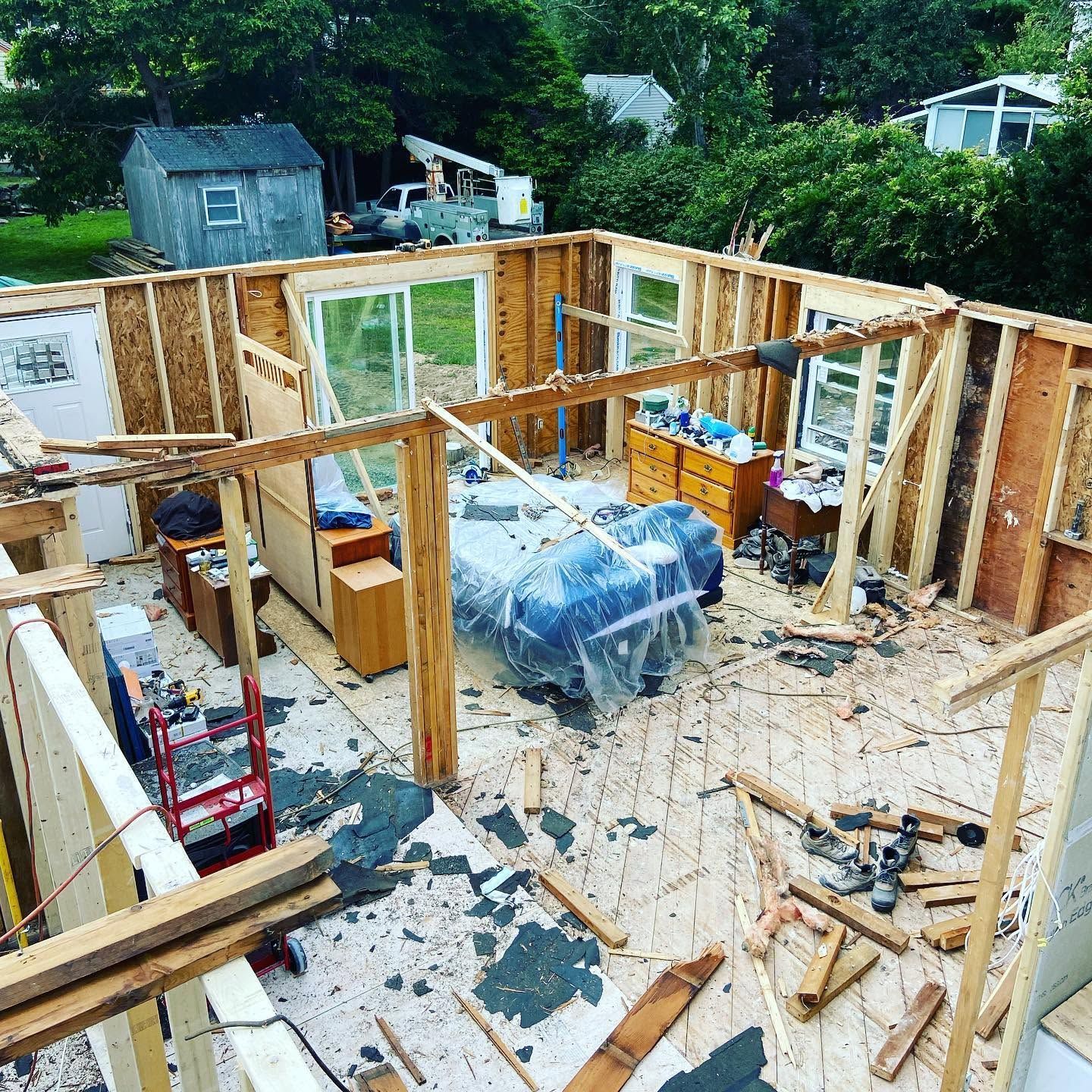 Framed house under construction with exposed wooden walls, tools, and materials inside a partially built room.