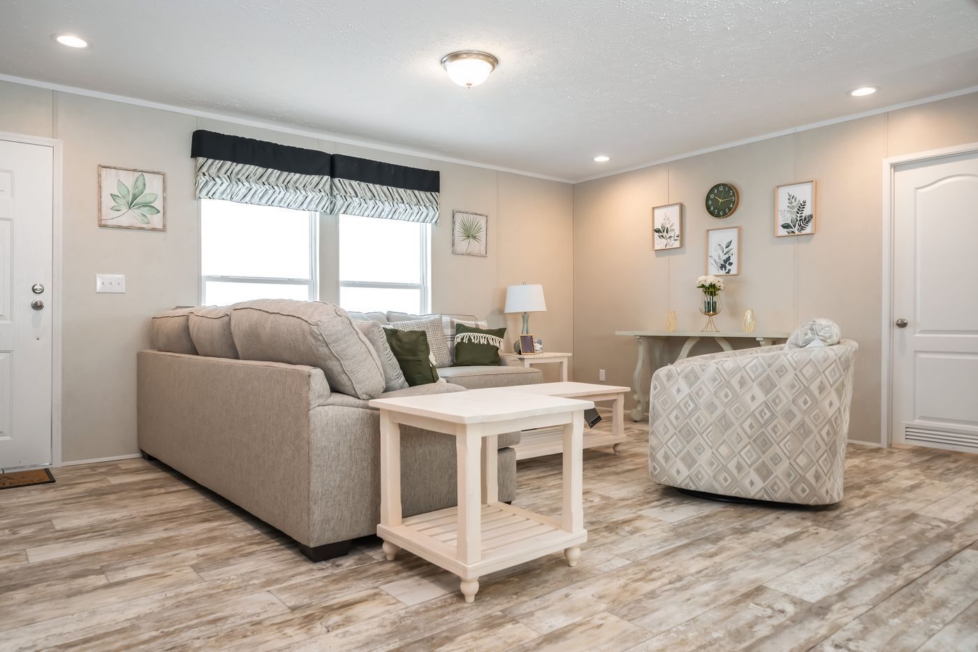 Living room with a sofa, armchair, side tables, and light-colored wood-look floors.