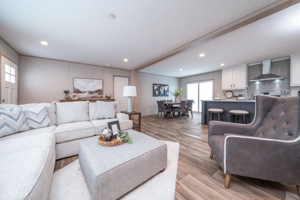 Modern living room with gray sectional, armchair, and open kitchen.