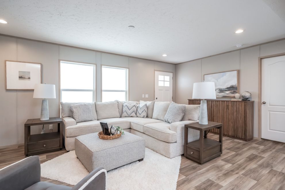 Cozy living room with sectional sofa, side tables, and rug, wooden flooring and neutral color walls.