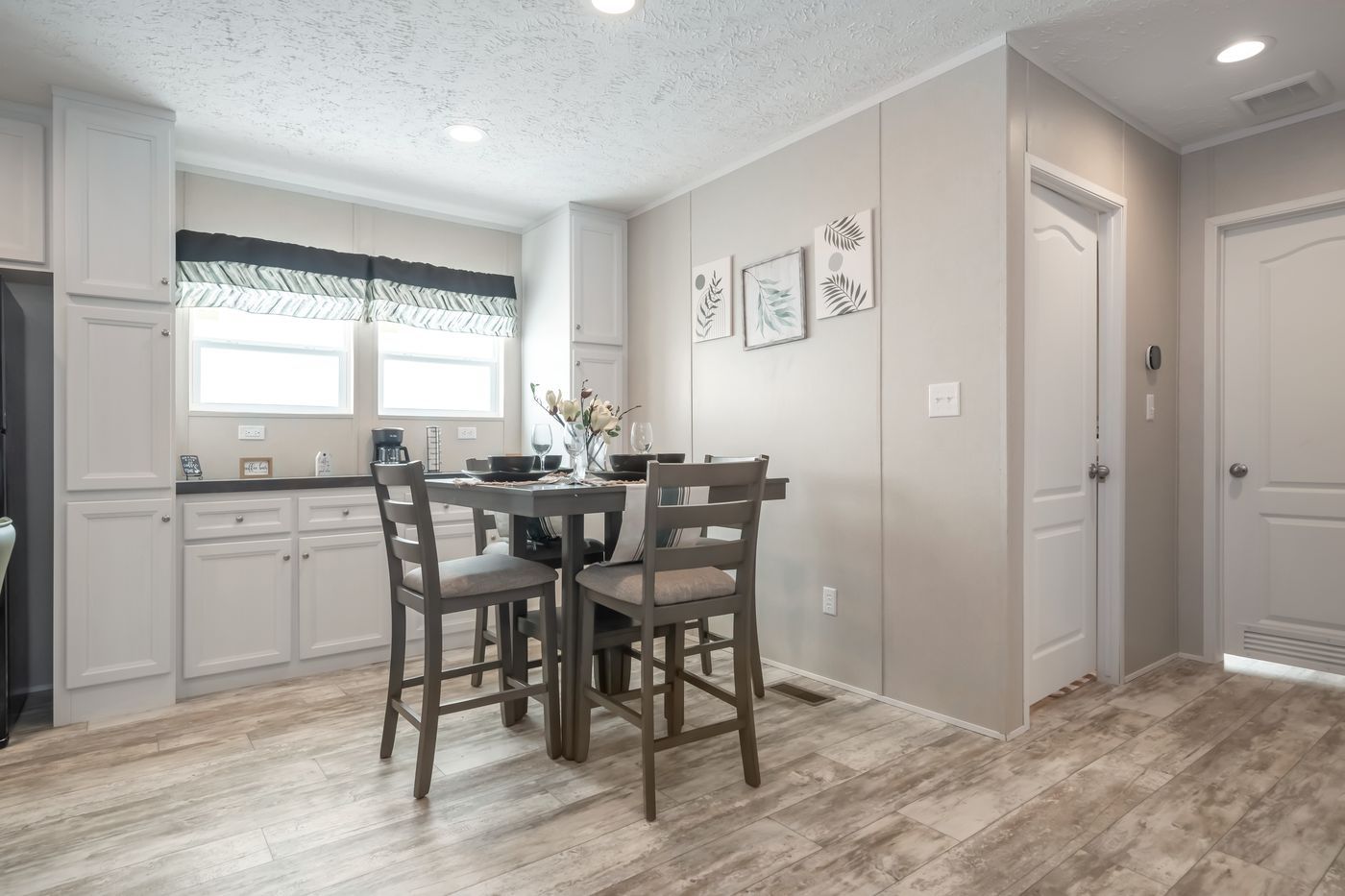 Dining area: gray table and chairs, light gray cabinets, white walls, and wood-look flooring.