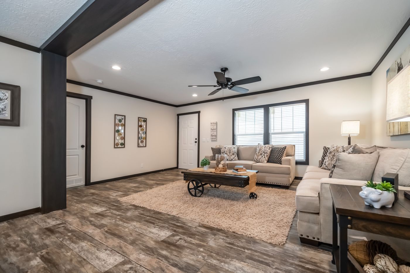 Living room with beige couch, rug, ceiling fan, and rustic wood-look flooring.
