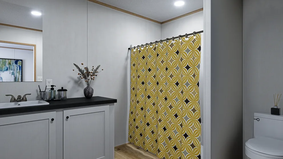 Bathroom with white cabinetry, black countertop, yellow geometric shower curtain, and toilet.