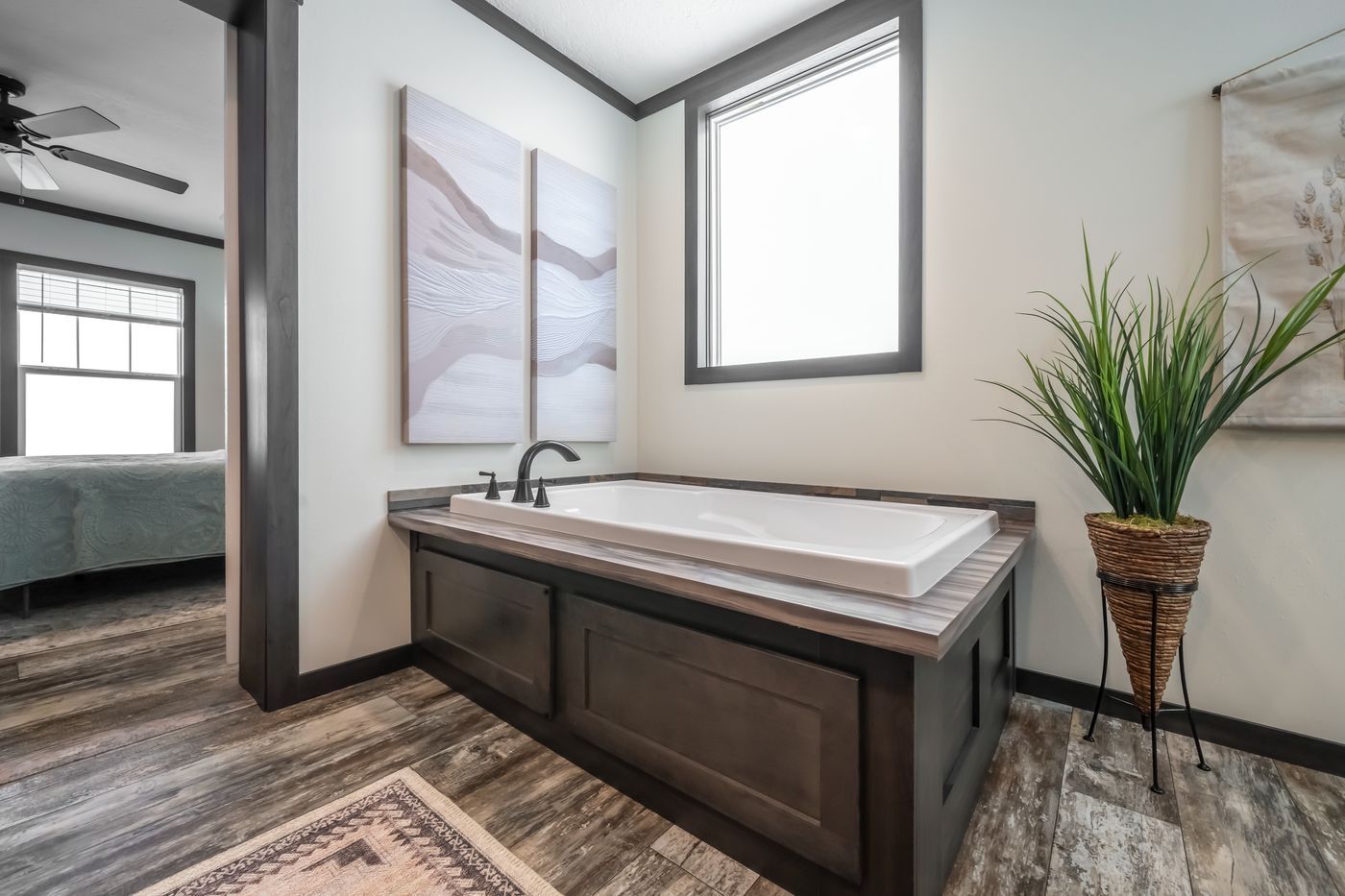 Bathroom with dark wood tub surround, large window, and decorative art.