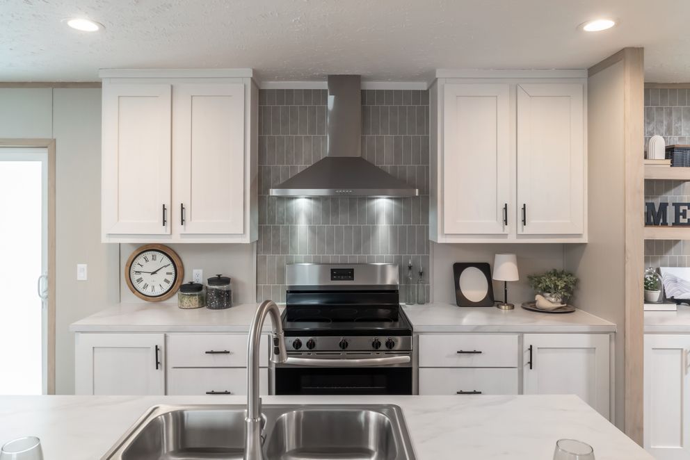 White kitchen with stainless steel appliances and gray tiled backsplash.
