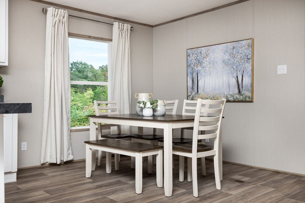 Dining room with a table, chairs, bench, window, and artwork. Light gray walls, wood-look floor.