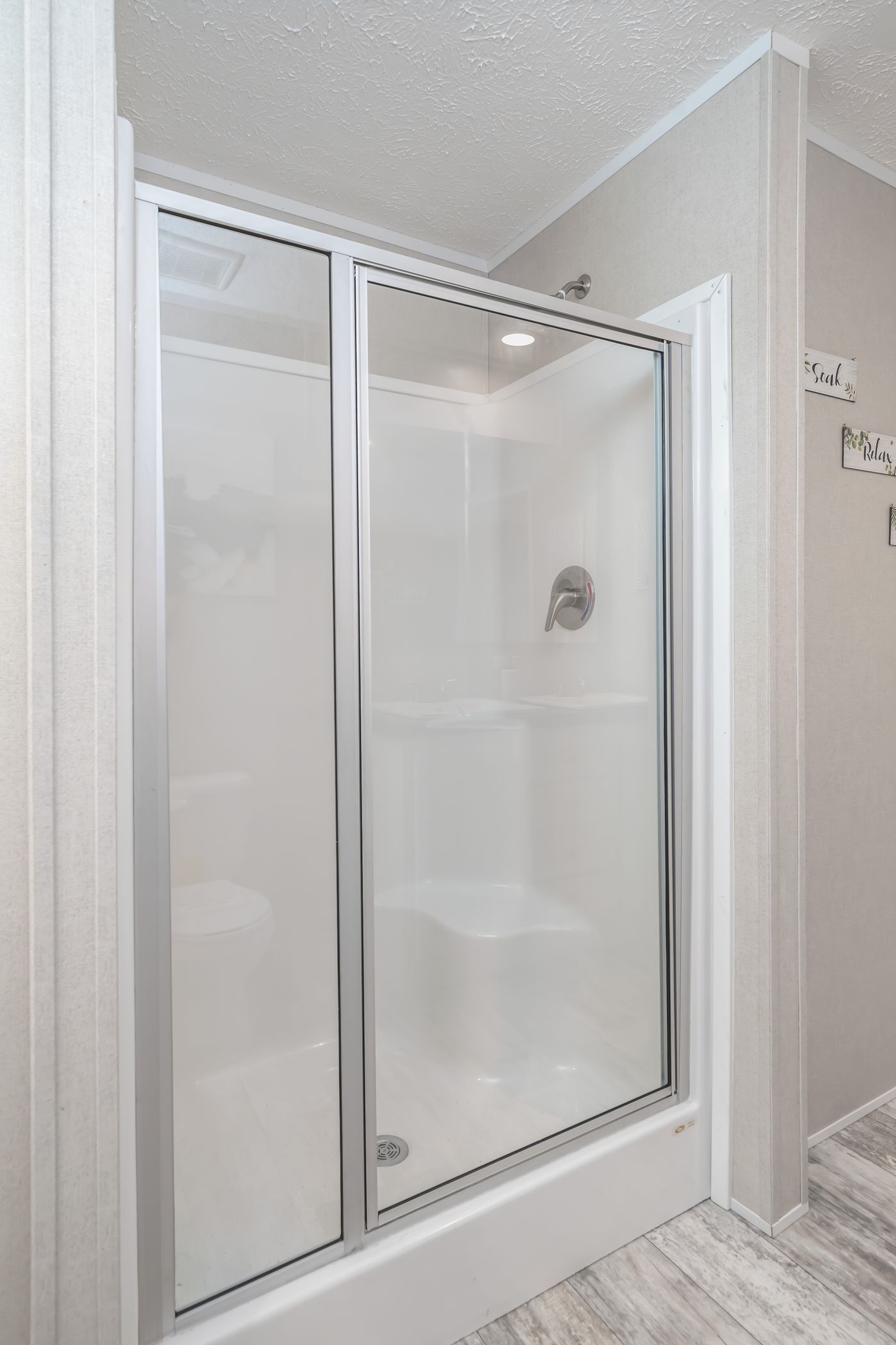 White and silver shower enclosure in a bathroom, with sliding glass doors.