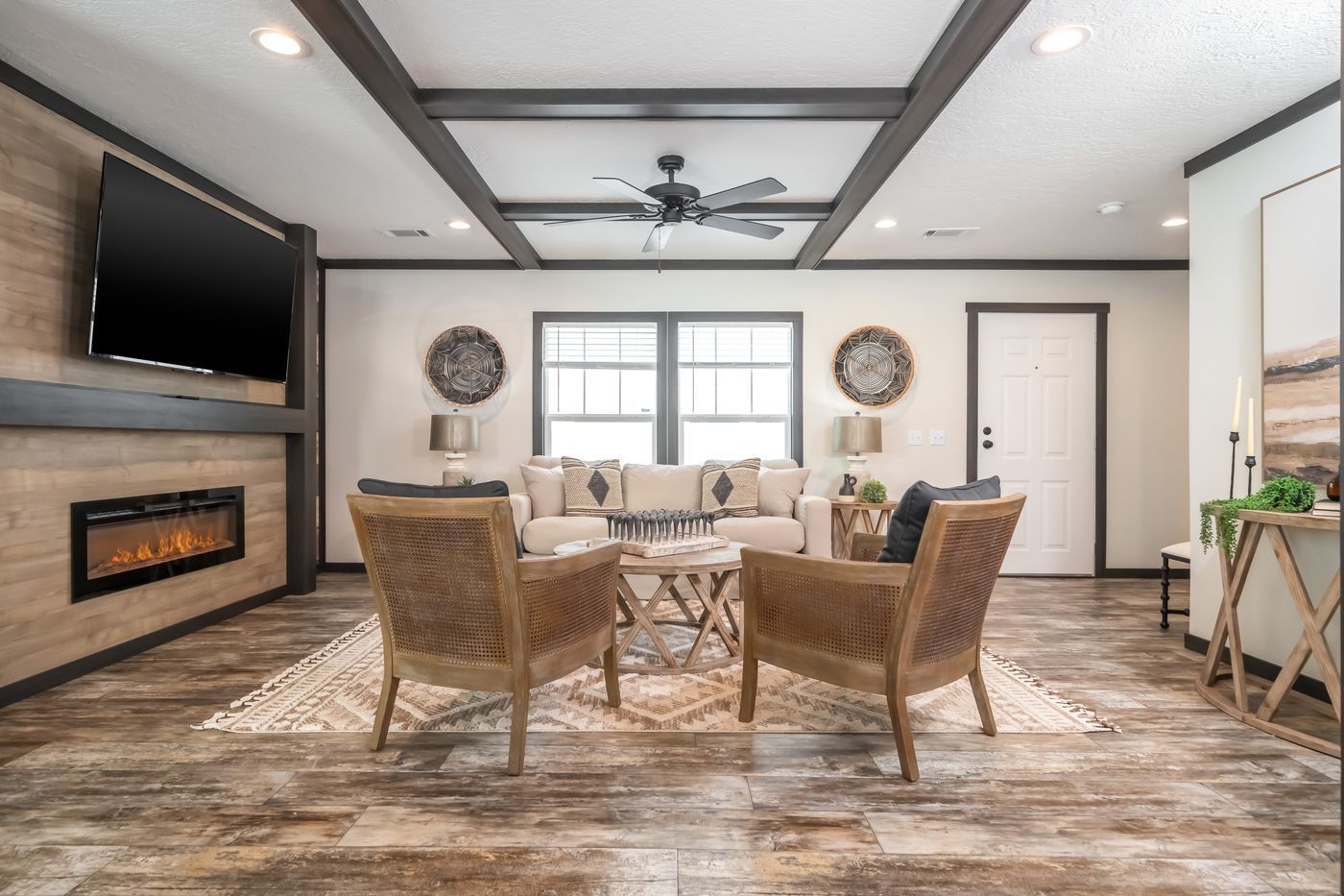 Living room with fireplace, wood beams, two chairs, and a couch.