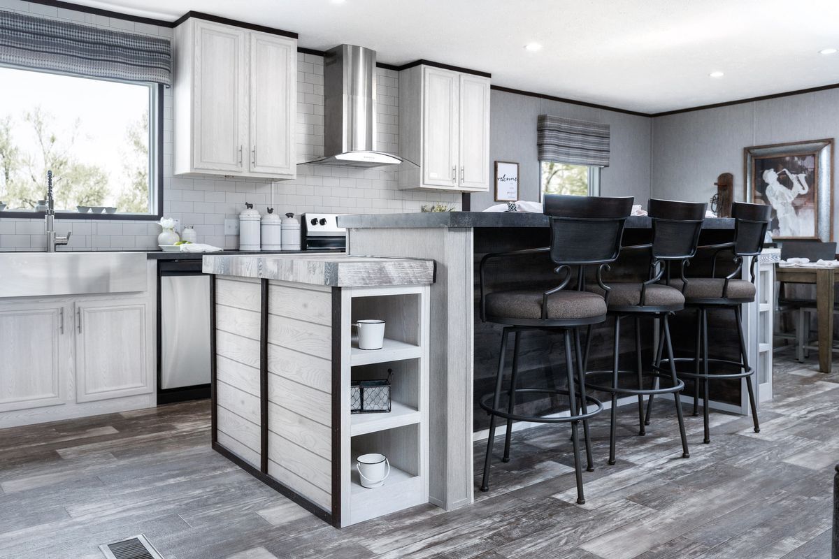 Modern kitchen with bar seating, light cabinets, gray countertop, and window.