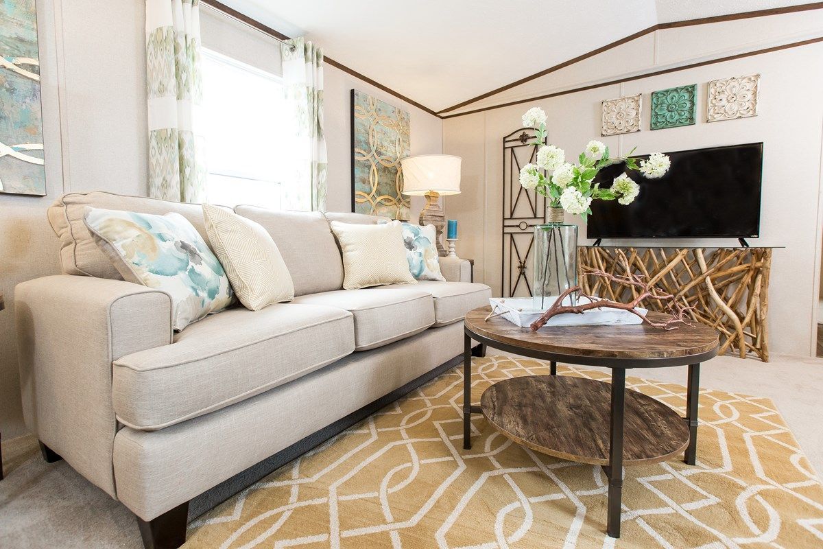 Living room with beige sofa, patterned rug, round coffee table, TV, and decorative items.