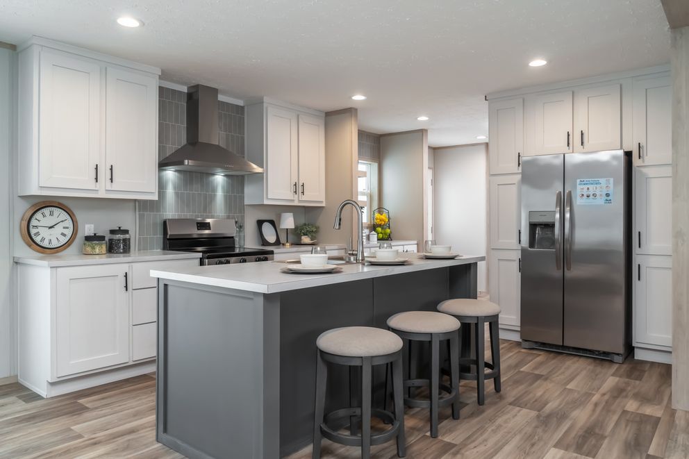 Modern kitchen with gray island, white cabinets, stainless steel appliances, and three bar stools.