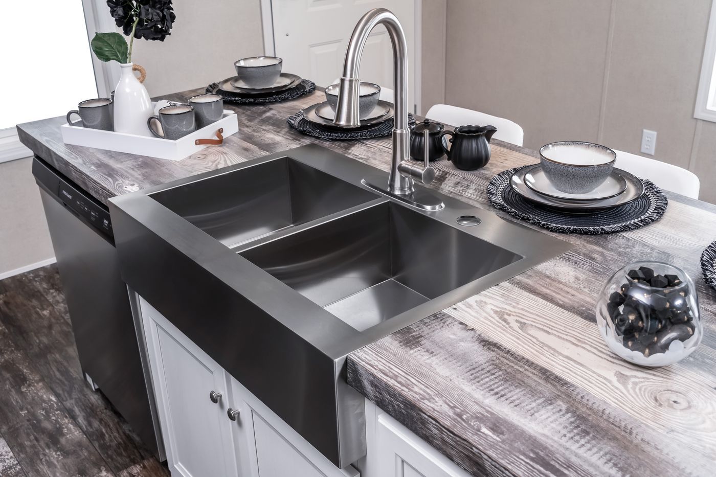 Stainless steel kitchen sink in a modern kitchen island, with place settings.