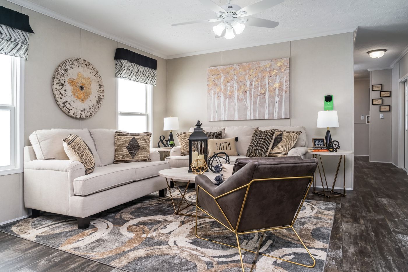 Cozy living room with neutral tones, sofa, accent chair, area rug, artwork, and natural light.