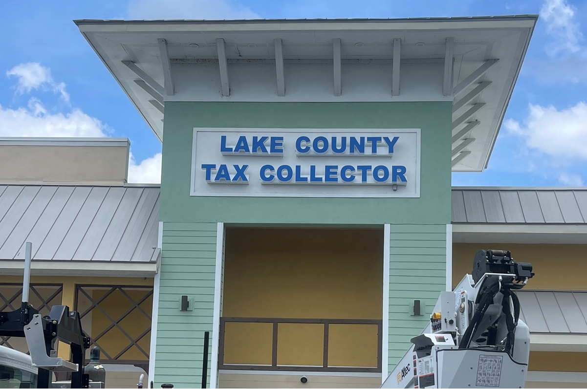 Lake County Tax Collector sign on a light green building under a blue sky