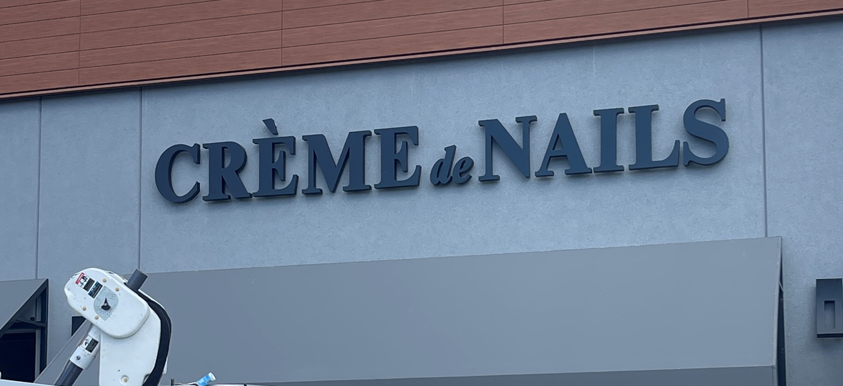 Storefront sign reading CRÈME de NAILS on a building.