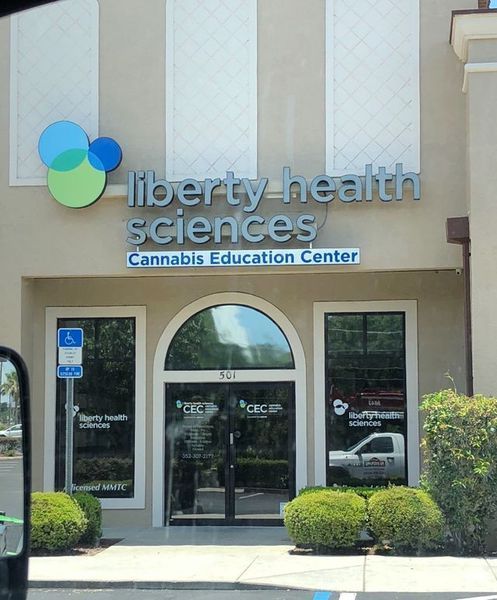 Exterior of Liberty Health Sciences, a cannabis education center, with signage and logo.