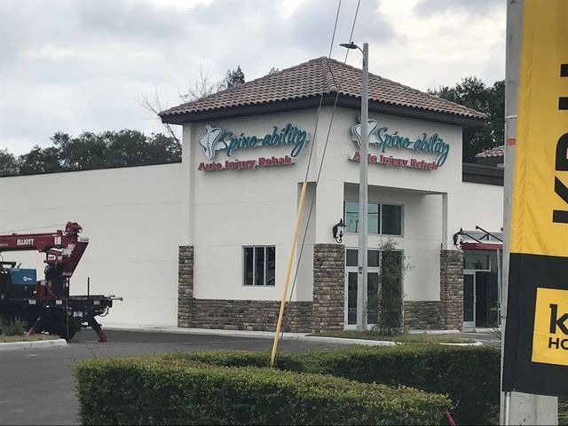Spine & Ability building with sign, red crane truck, and shrubbery in front.