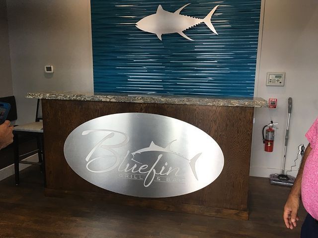 Reception desk with a Bluefin logo, a blue wall with a tuna, and a granite countertop.