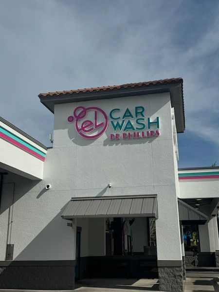 White car wash building with teal and pink accents, sign says 