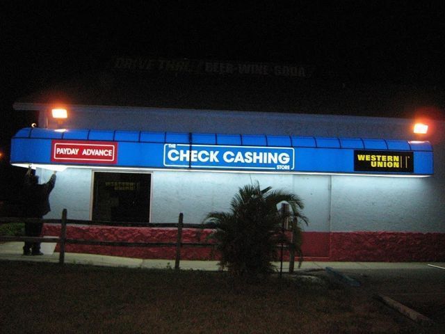 Nighttime exterior of a check cashing business with blue awning, 