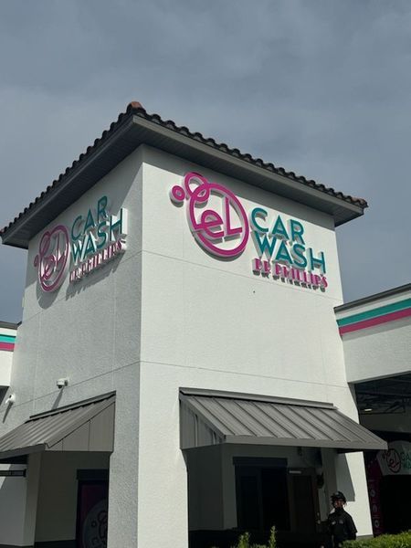 Car wash building with pink and teal logo. 