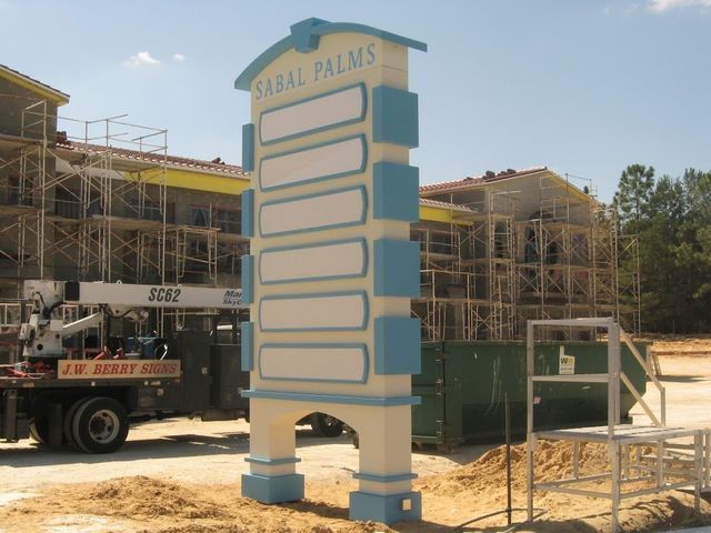 Sign for Sabal Palms, light blue and white with blank panels, in front of a construction site.