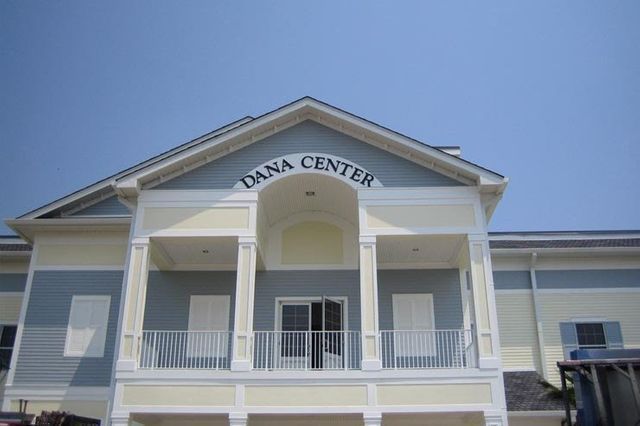 Dana Center building exterior with light blue and yellow siding under a clear, blue sky.