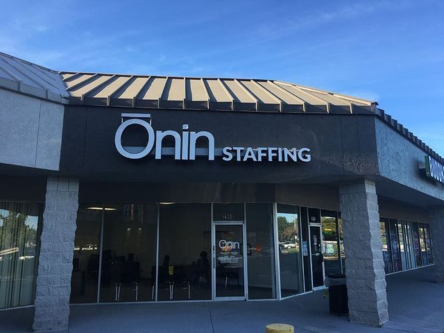 Onin Staffing storefront with white sign on a gray building, blue sky.