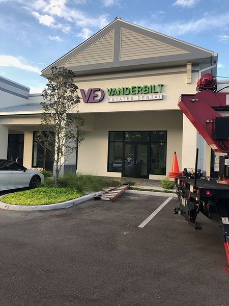 Exterior of Vanderbilt Center Dental office with green and purple logo; red truck in the parking area.