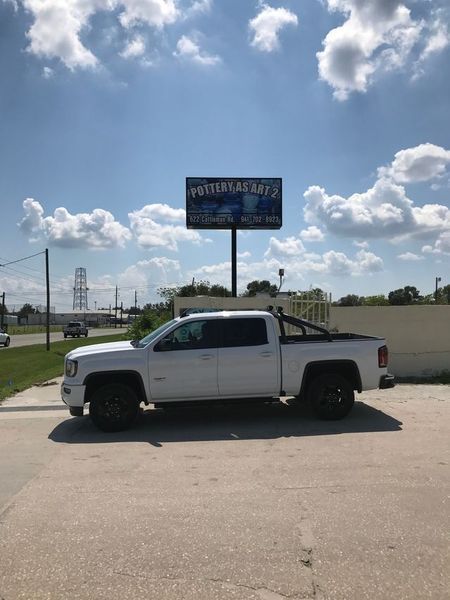 White pickup truck parked under a blue sky with a business sign in the background.